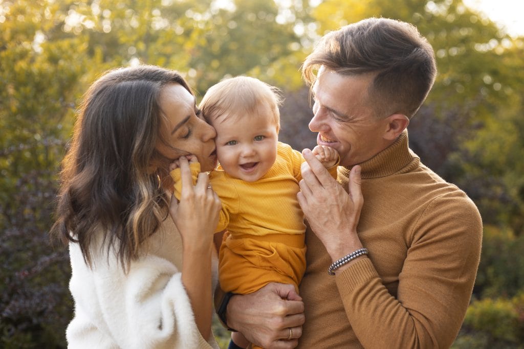 Parents holding and hugging child. 