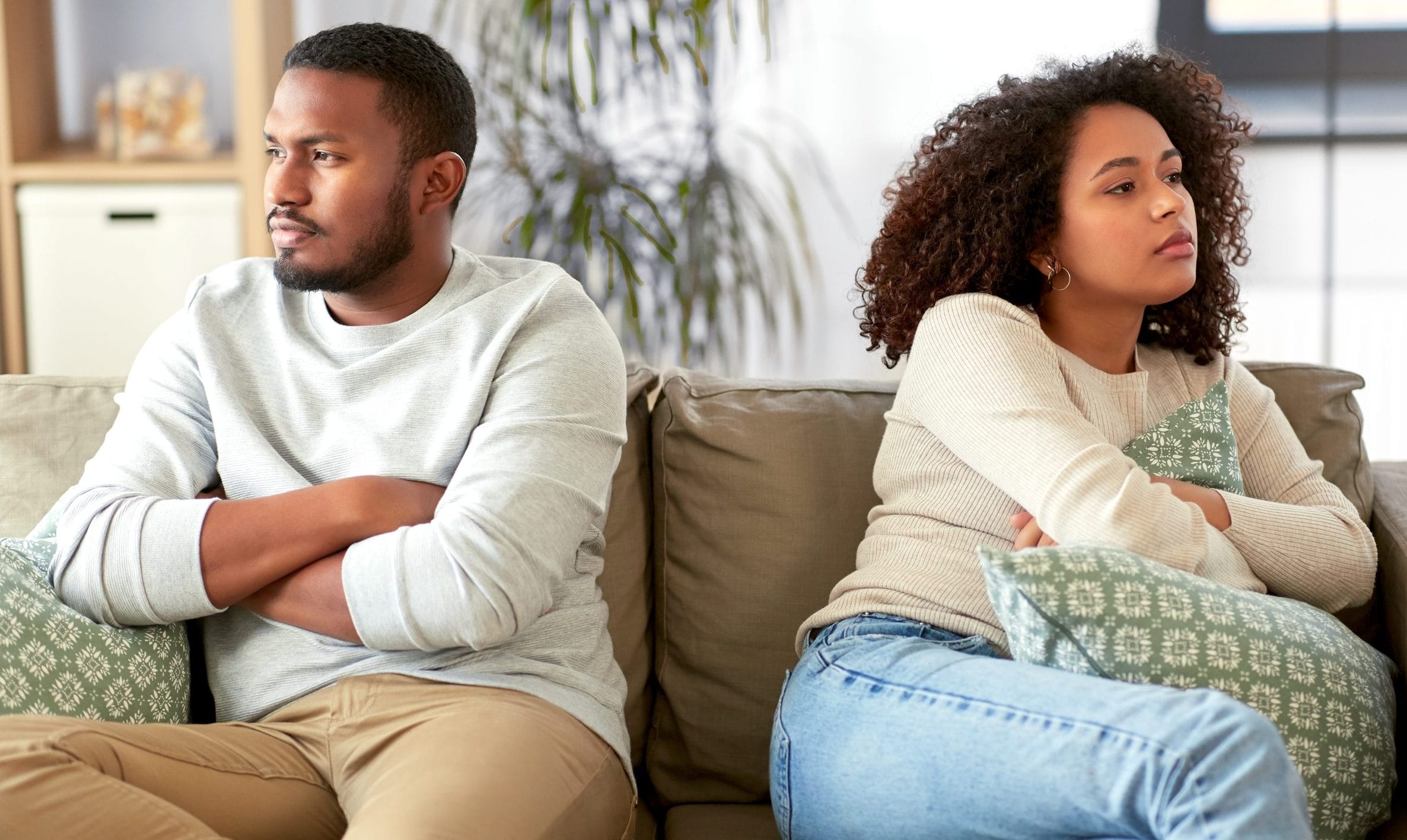 Married couple living together but emotionally separated while sitting on the same couch.